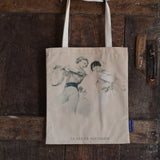 Tote bag with a vintage line-drawn image featuring two young lovers with the text 'Le Pas de Fantaisie' hanging next to a dark wooden door