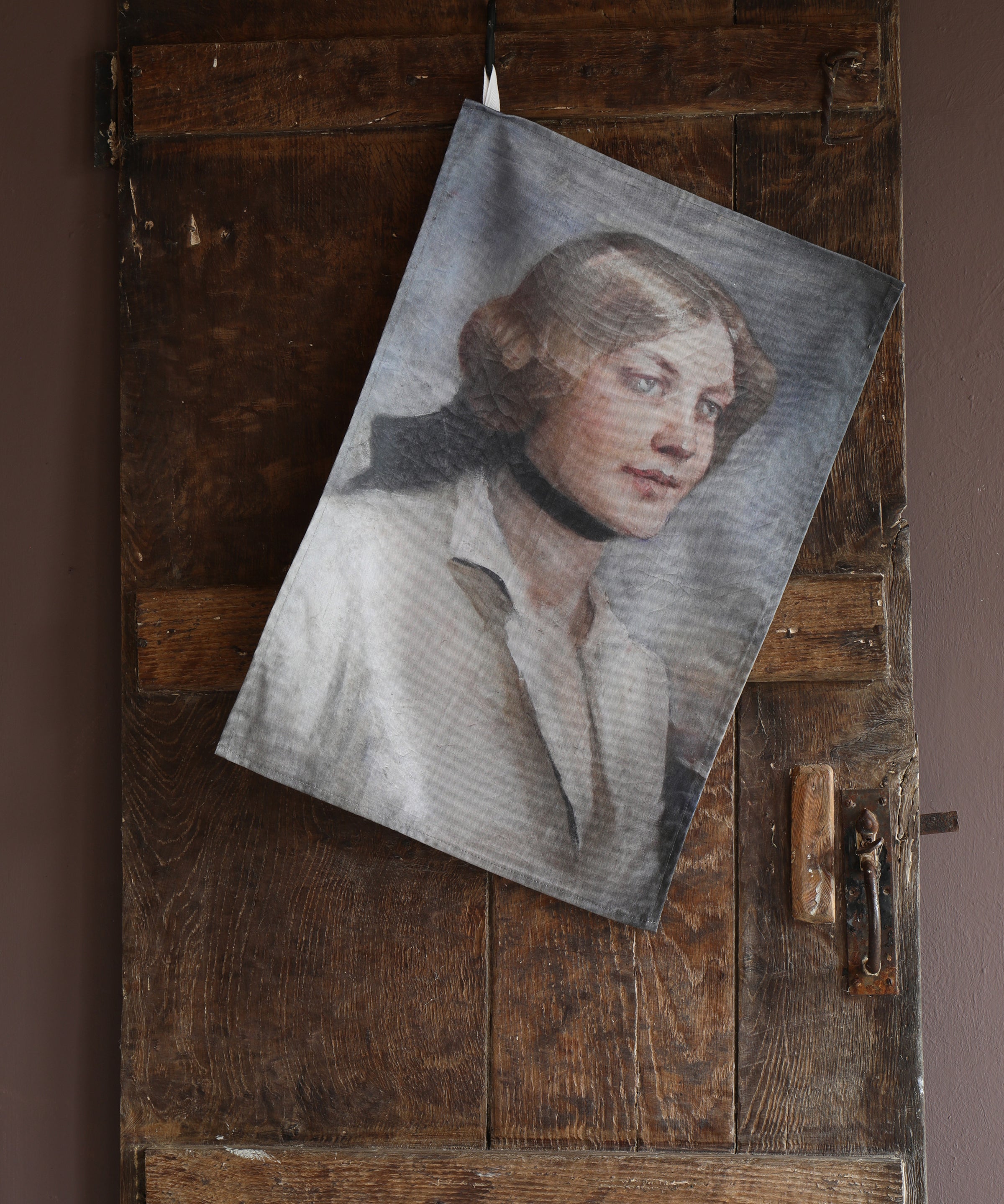 Vintage-style portrait of a woman printed on a tea towel hanging on a rustic wooden door