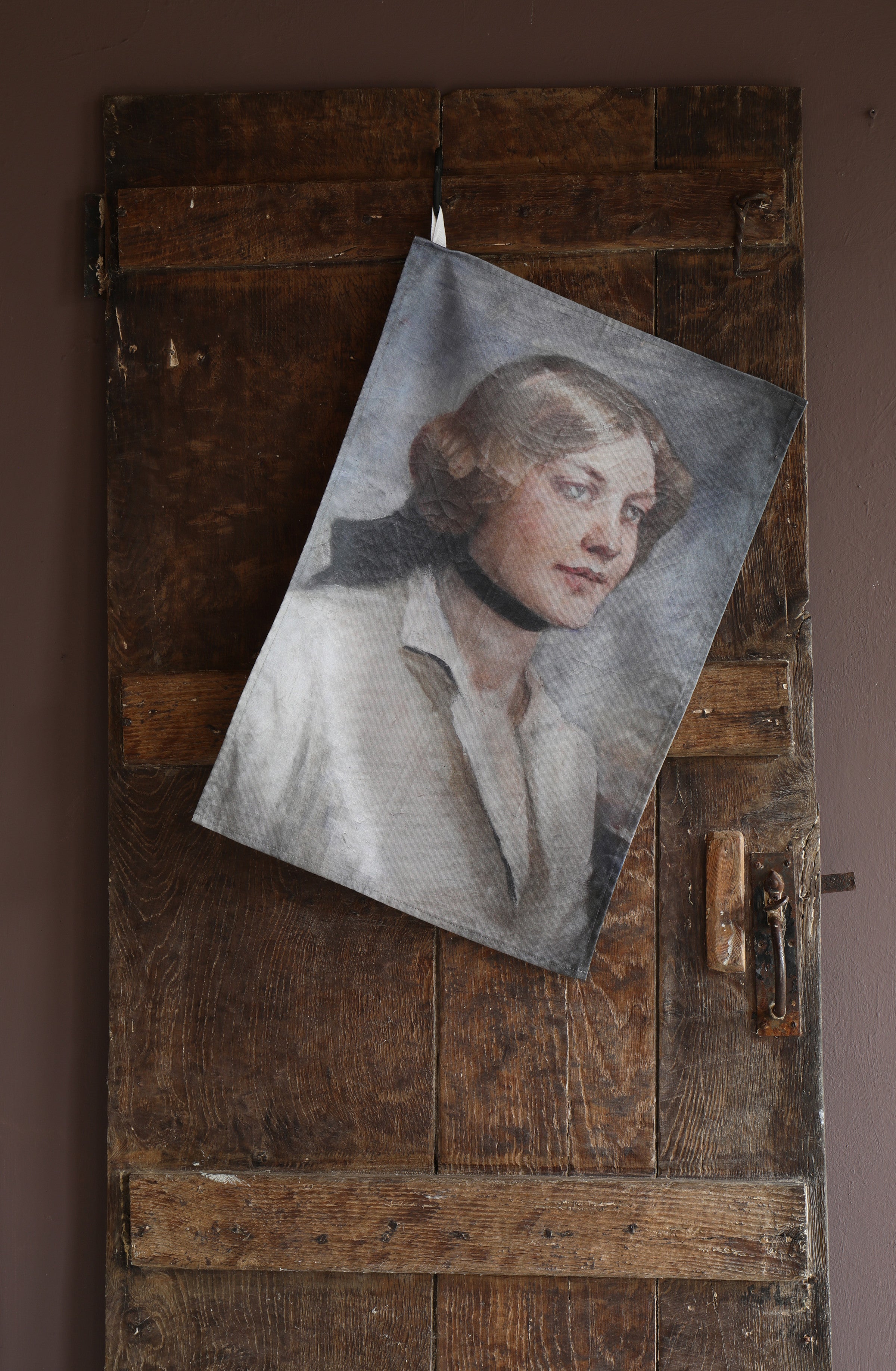 Vintage-style portrait of a woman printed on a tea towel hanging on a rustic wooden door