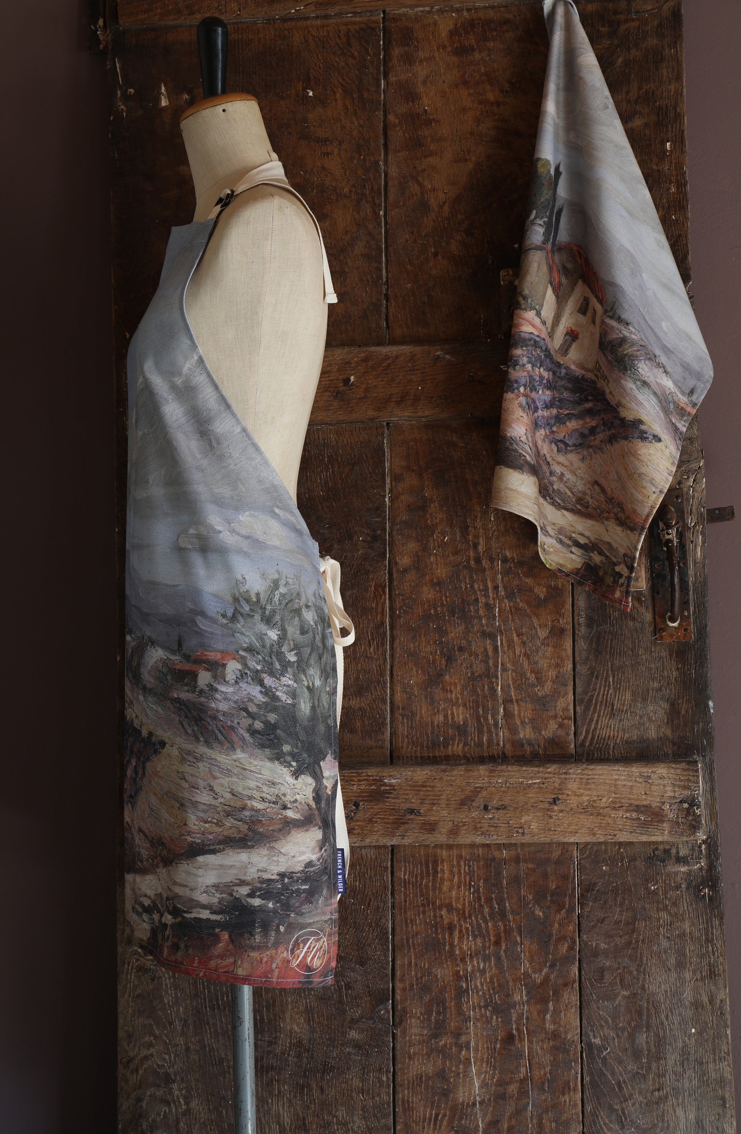 Mannequin wearing an apron with a design of a rural Provence design against a wooden background