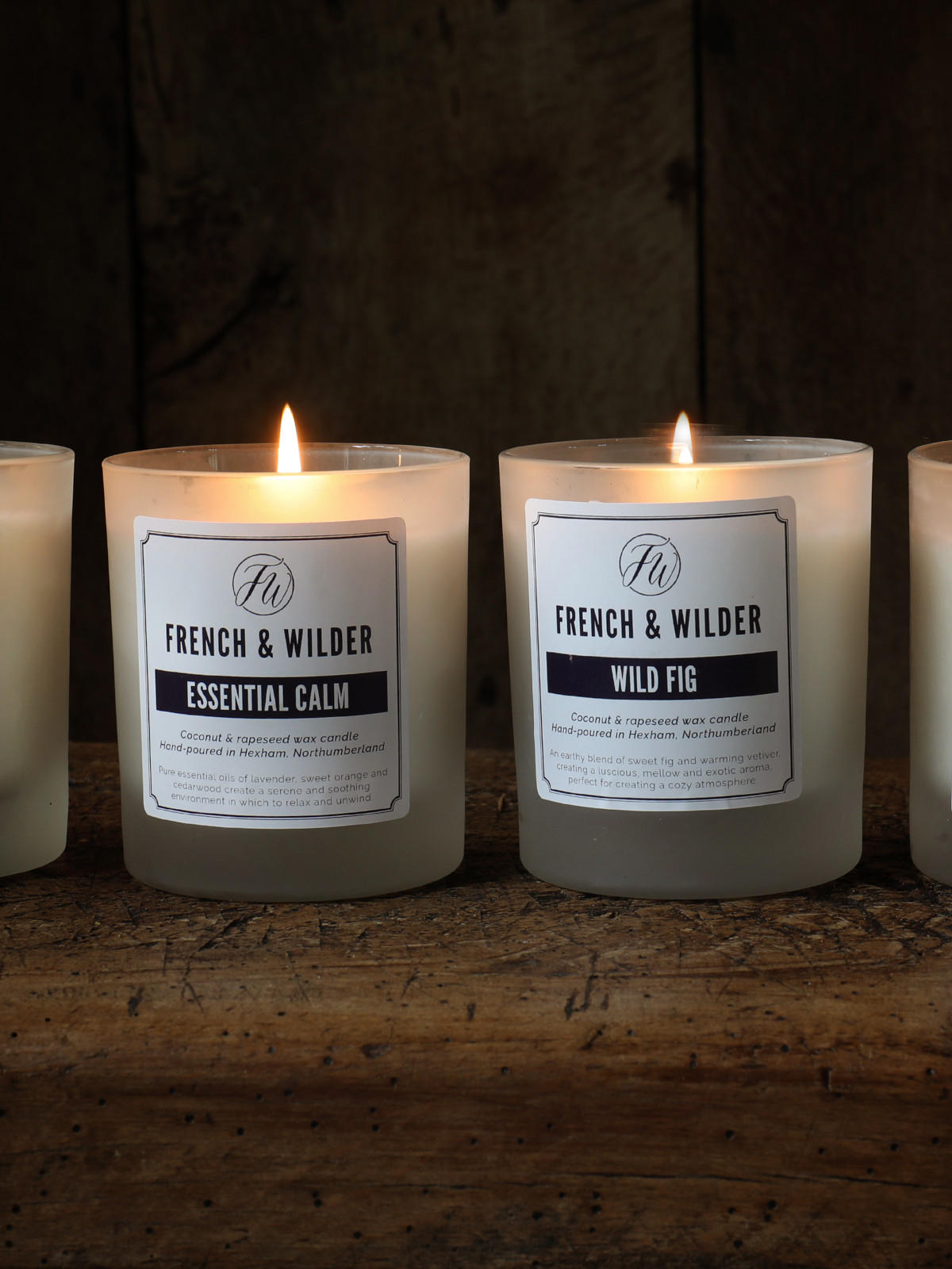 Four lit candles with French & Wilder labels on a dark background
