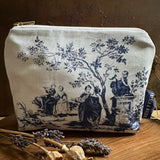 Fabric pouch with vintage toile de jouy design on a wooden surface with dried flowers.