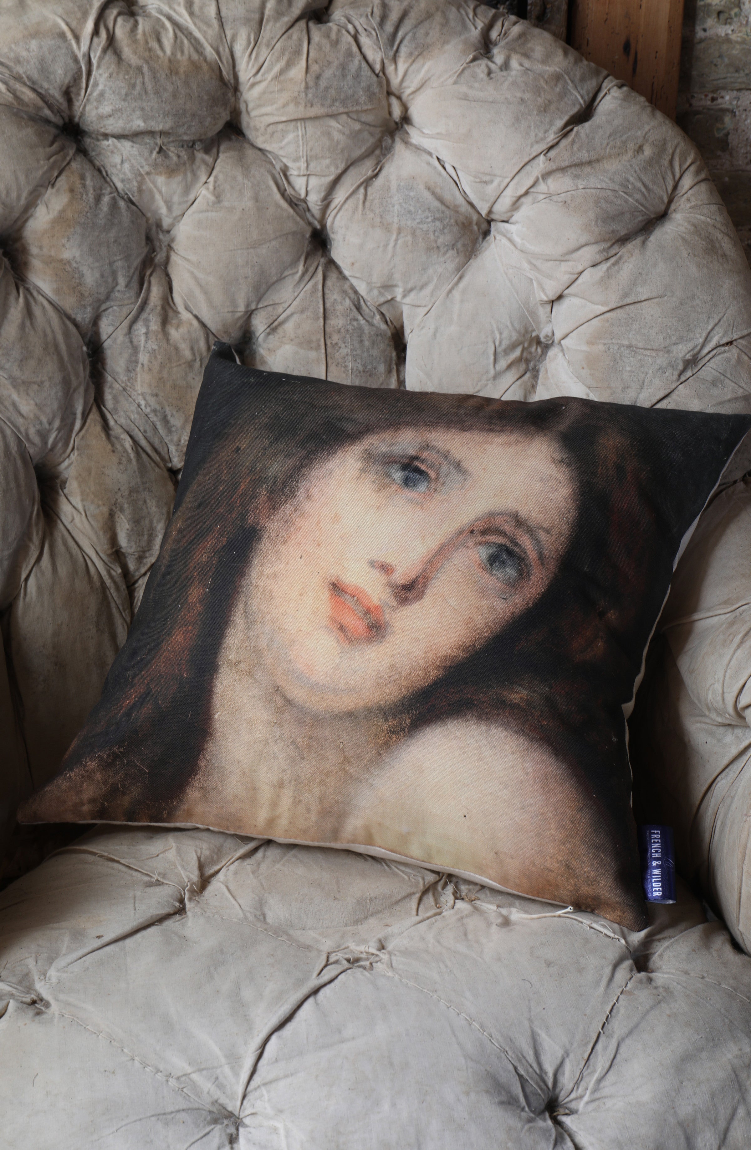 Decorative cushion with a woman portrait design placed on a vintage beige armchair