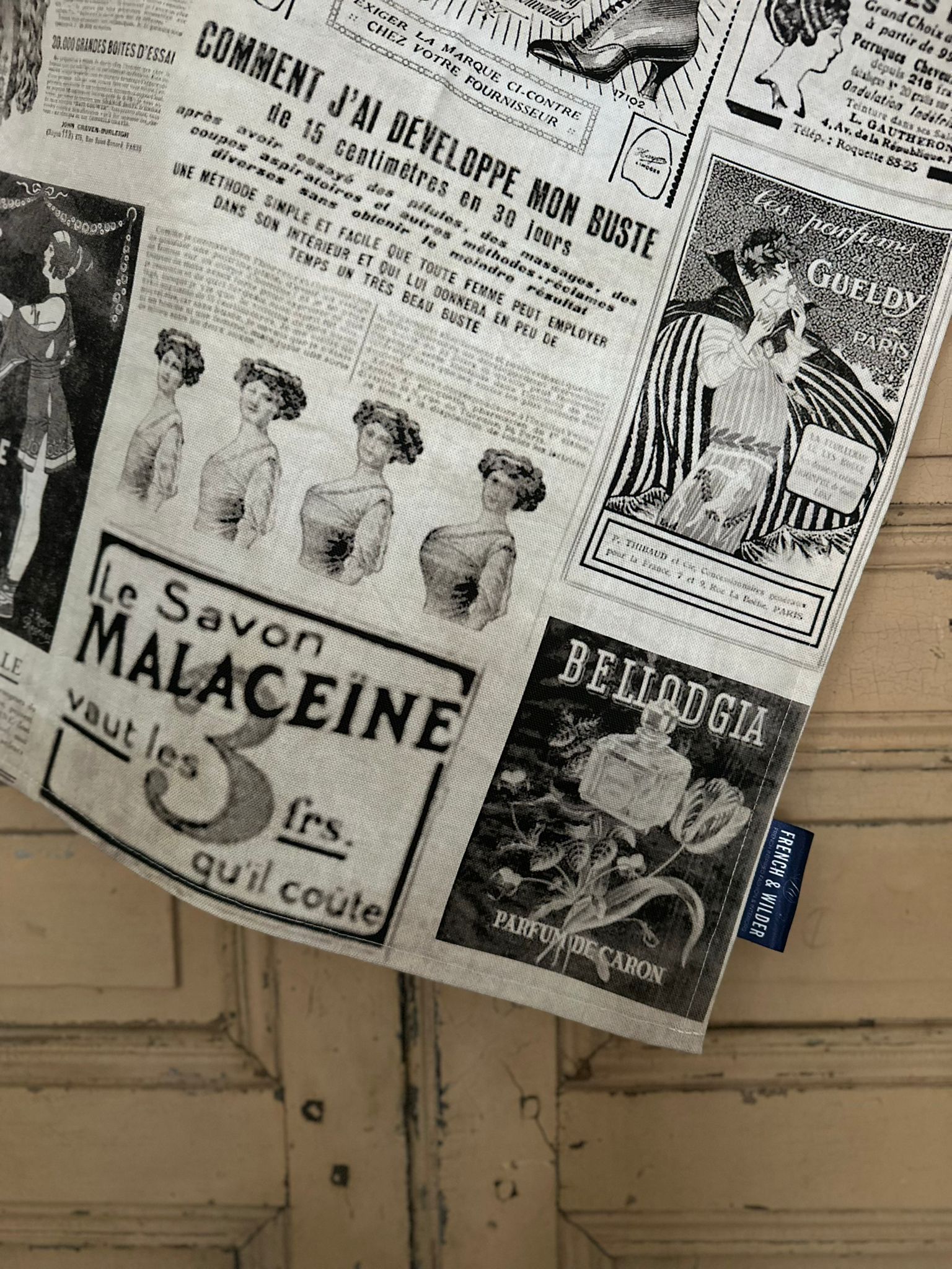 Tea towel featuring a collage of vintage magazine adverts in black and white against a painted wooden surface