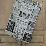Tea towel with a design of vintage French beauty and fashion advertisements hanging next to a painted wooden door