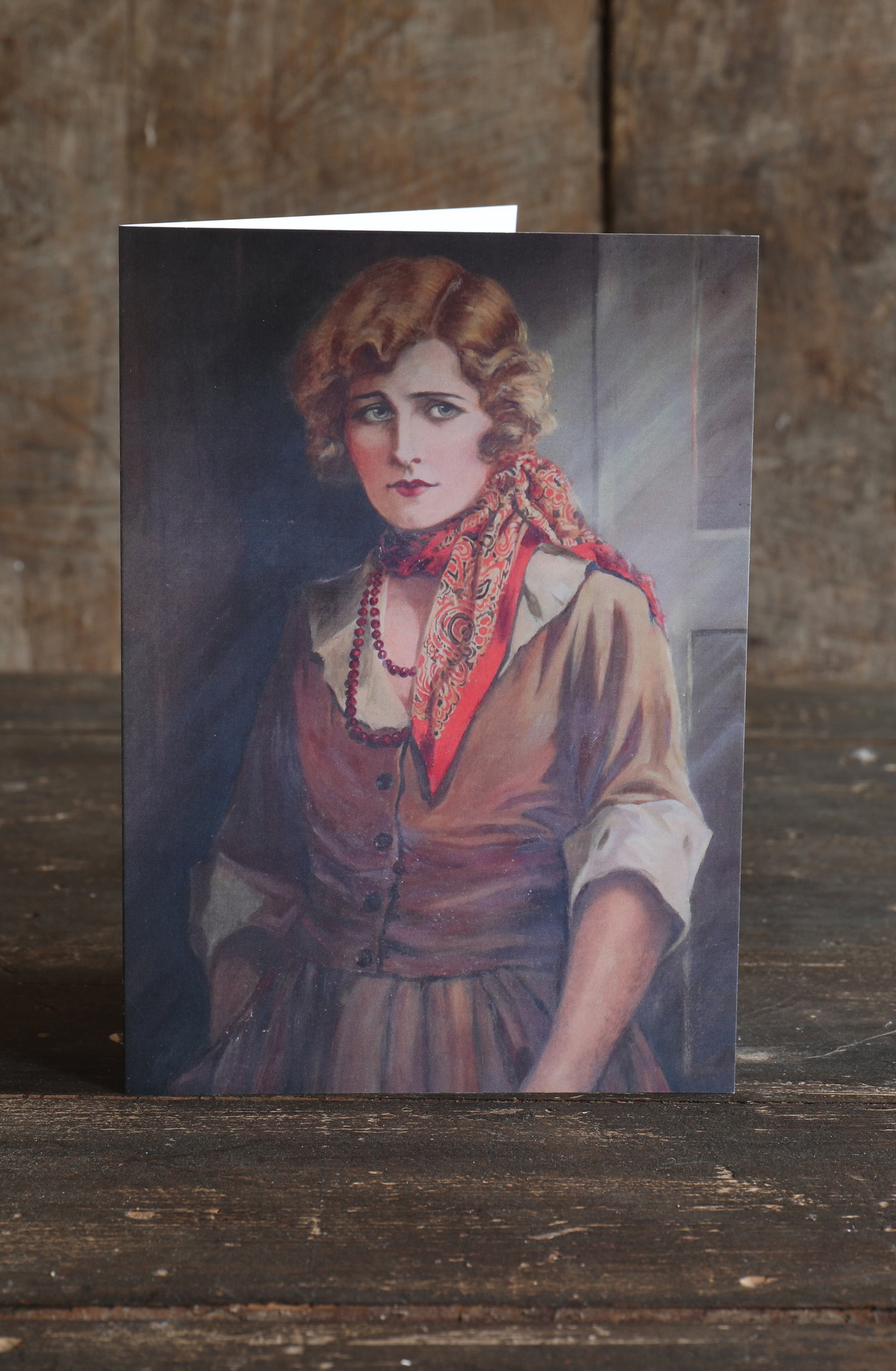 Greetings card with a vintage portrait of a woman dressed in early 20th century fashion on a wooden surface