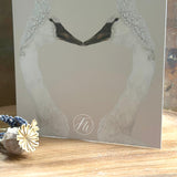 Greetings card featuring a design of two swans touching beak to beak with the FW logo, placed on a wooden surface.