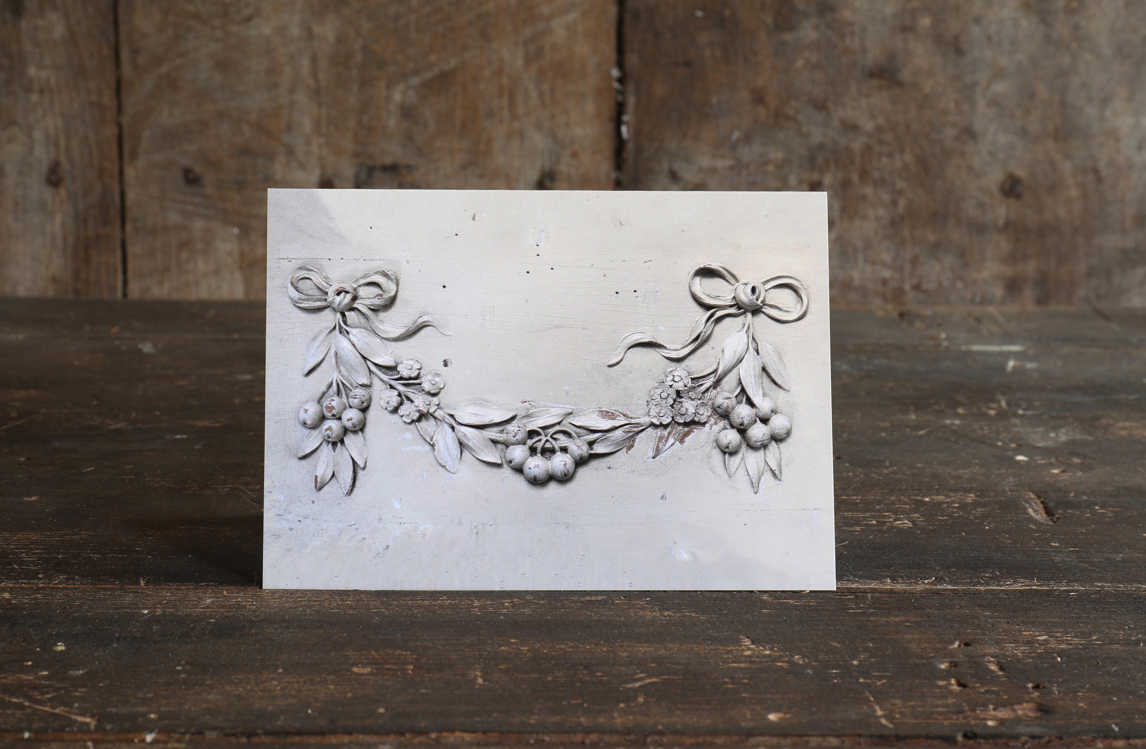 Greetings card with a design created from a floral wooden wall plaque placed on a wooden surface
