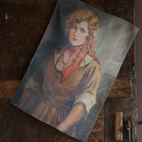 Tea towel featuring the vintage portrait of a woman with a serious gaze in elegant early 20th century fashion hanging from a dark wooden door