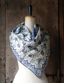 Mannequin wearing a blue and white tile pattern scarf against a wooden background
