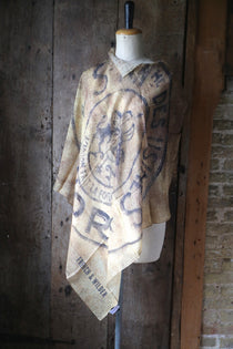 Mannequin wearing a scarf with a design from a vintage hessian sack with branding against a rustic brick wall.