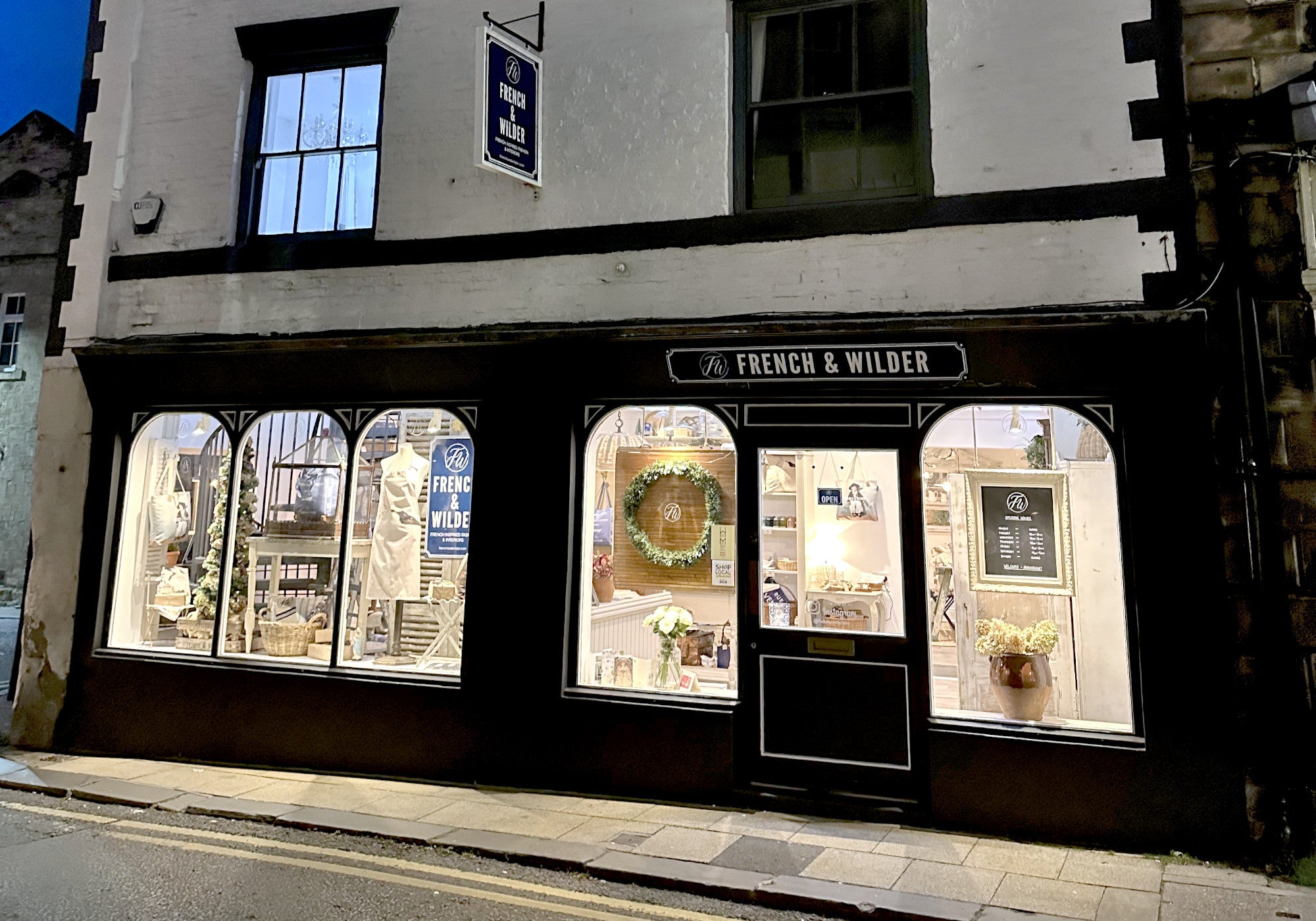 French & Wilder shop front at night time with large windows displaying homeware and fashion items