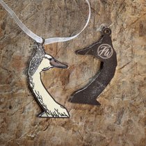 Swan-shaped pendant with white organza ribbon on a textured wooden surface